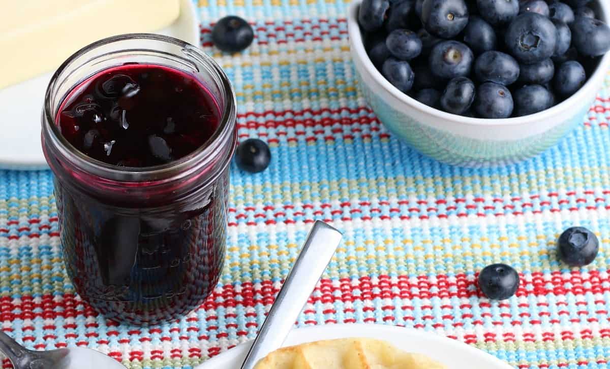 Wide photo of a jar full a complete blueberry sauce recipe.