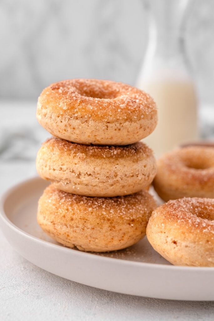vegan cinnamon-sugar donuts are stacked on a plate