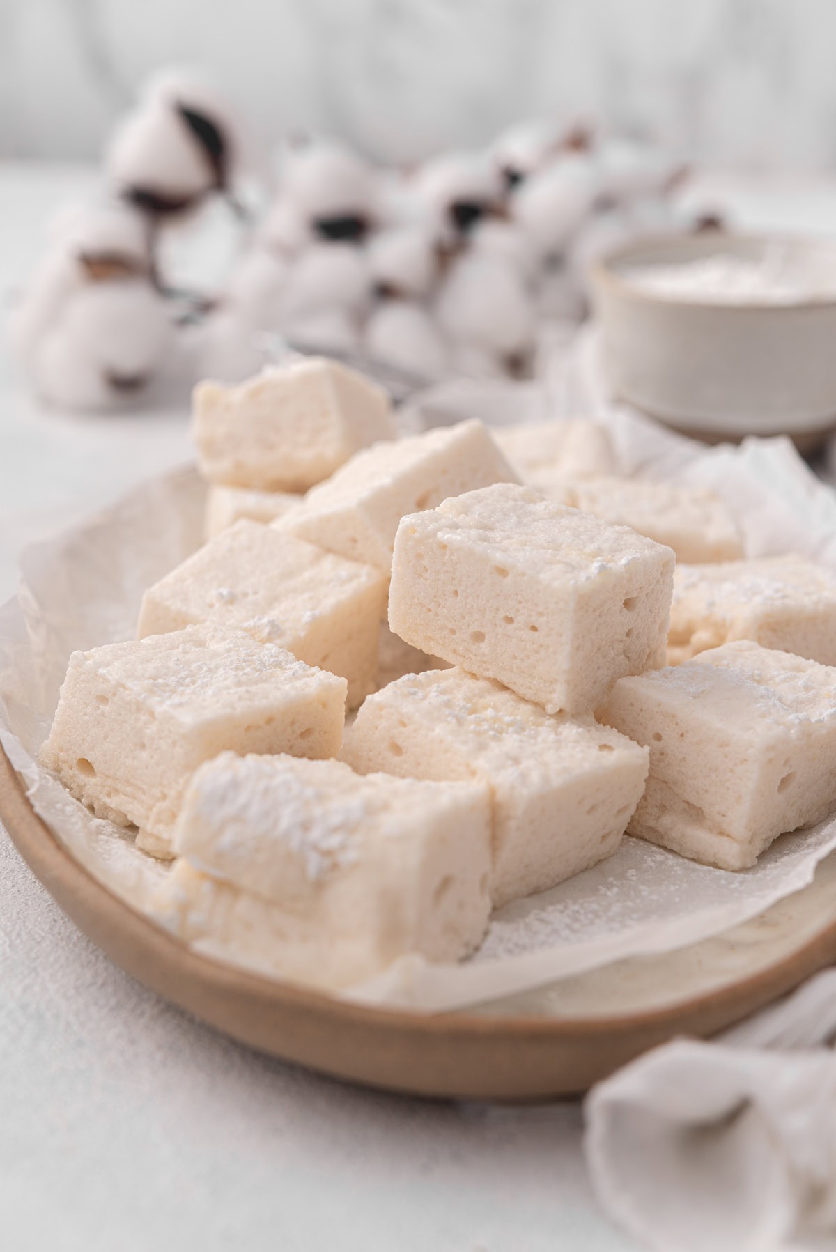 homemade vegan marshmallows are sliced into rectangles and sprinkled with powdered sugar on a platter